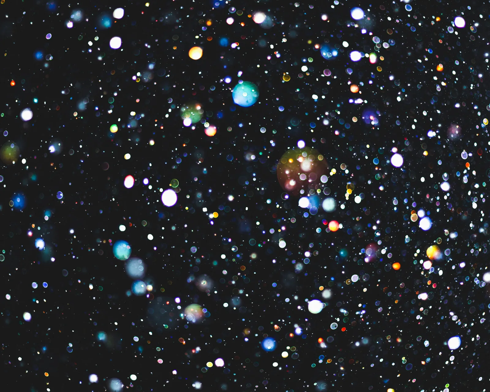 Multicoloured glitter suspended against a dark background