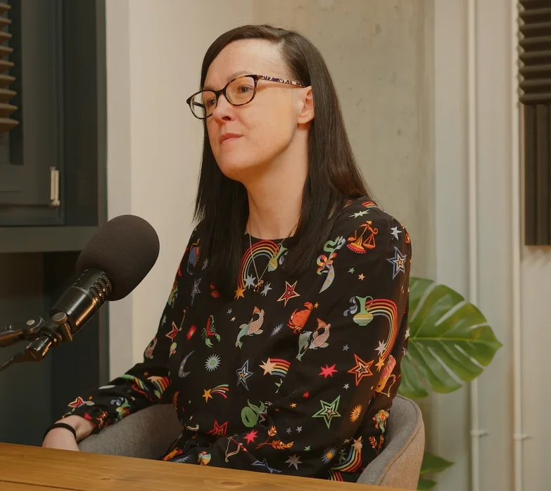 Clare E Kenny speaking into a podcast microphone