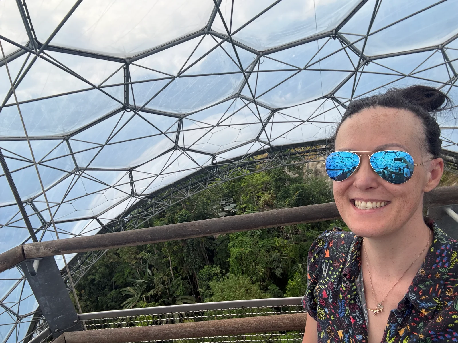 Clare beneath a glass dome surrounded by plants.